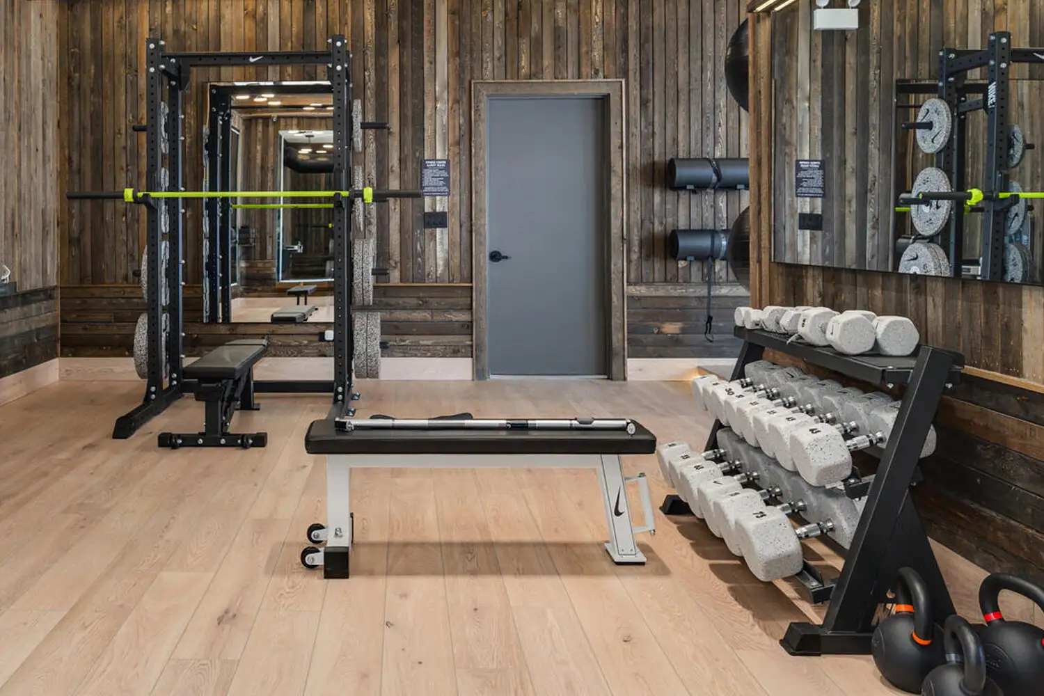 Wood-paneled strength room with a half rack, bench and dumbbell rack