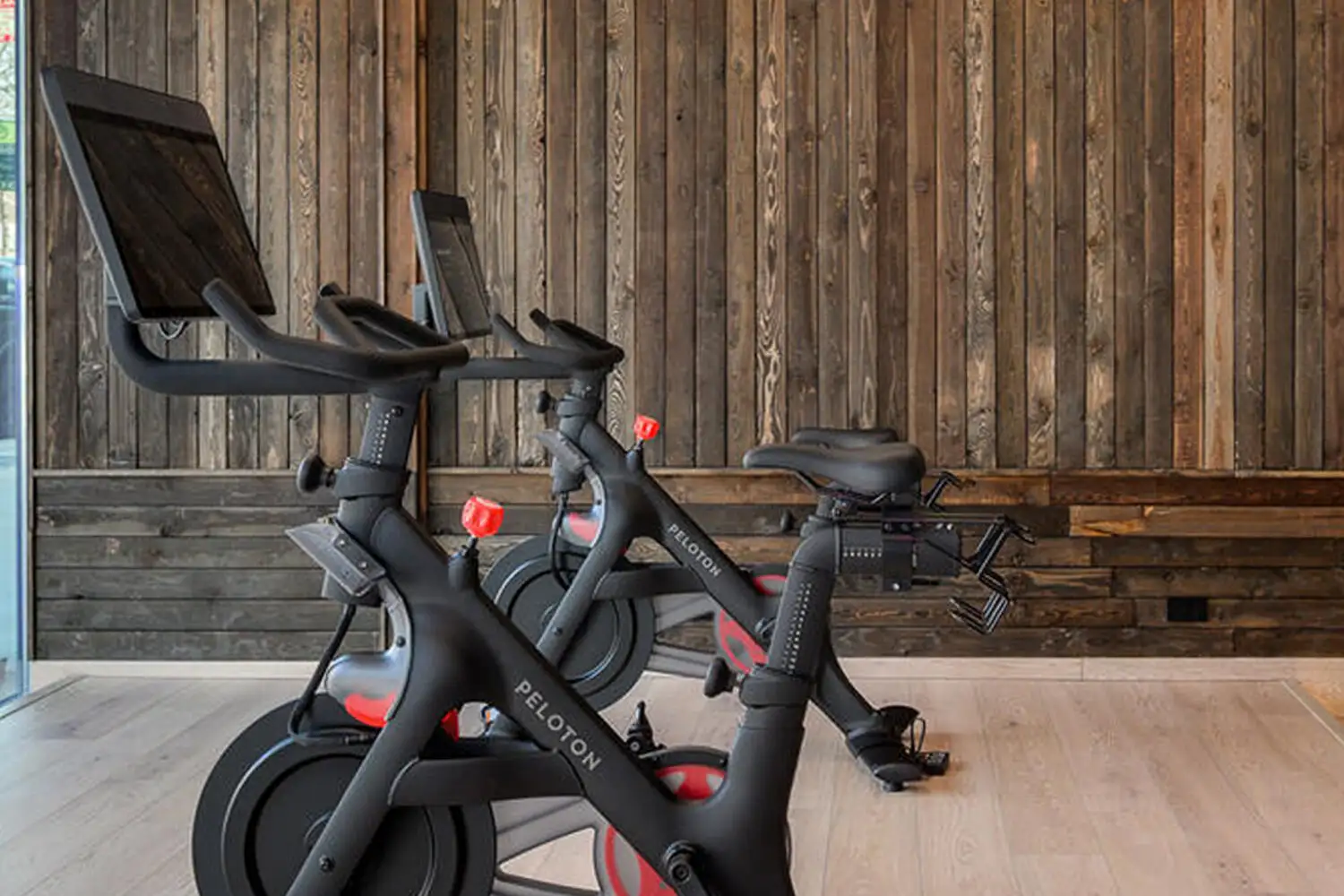 Two Peloton bikes against a reclaimed wood wall